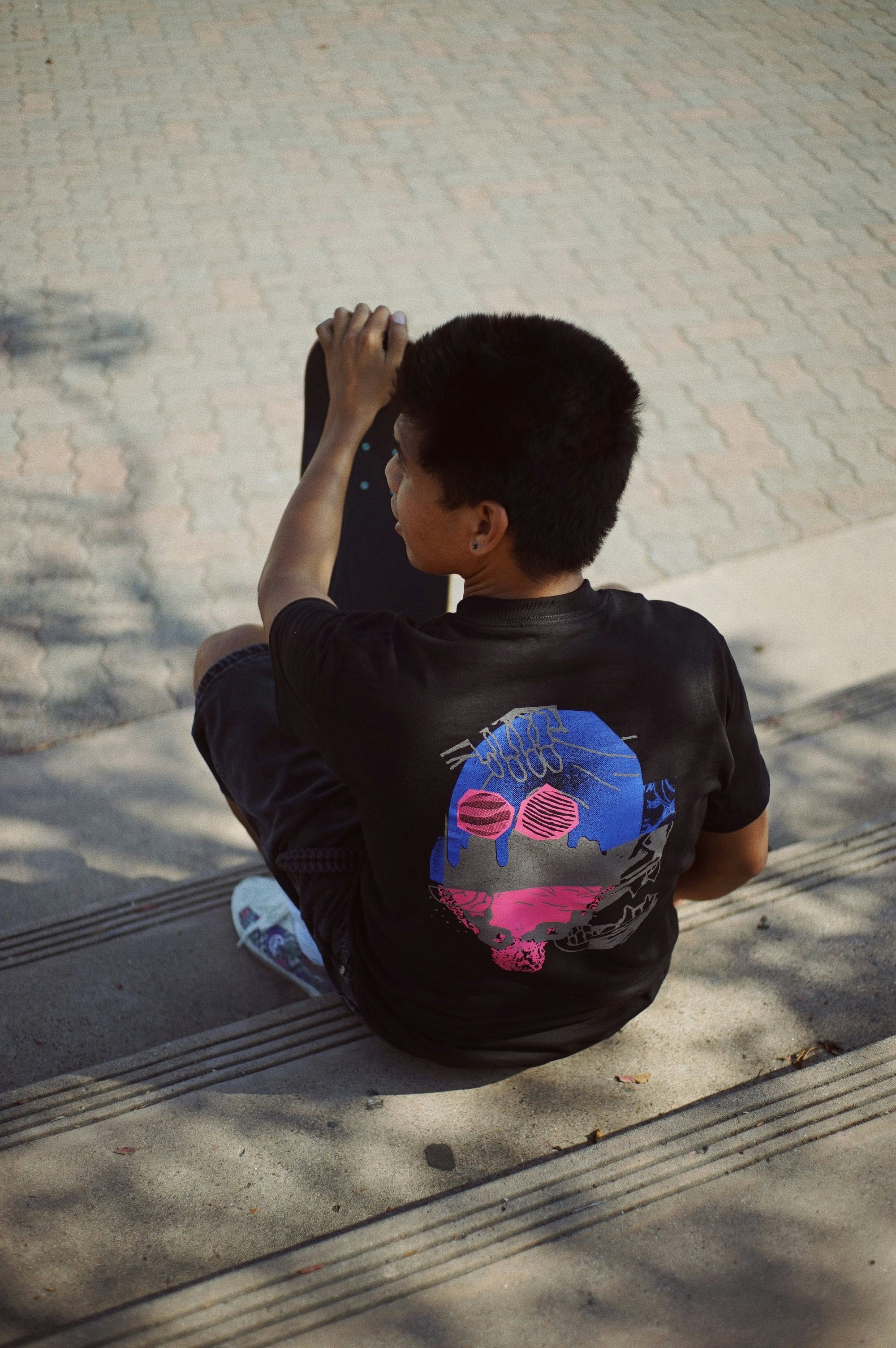 Flatspot AW21 Collection graphic tee in black shot on a model sitting on concrete steps