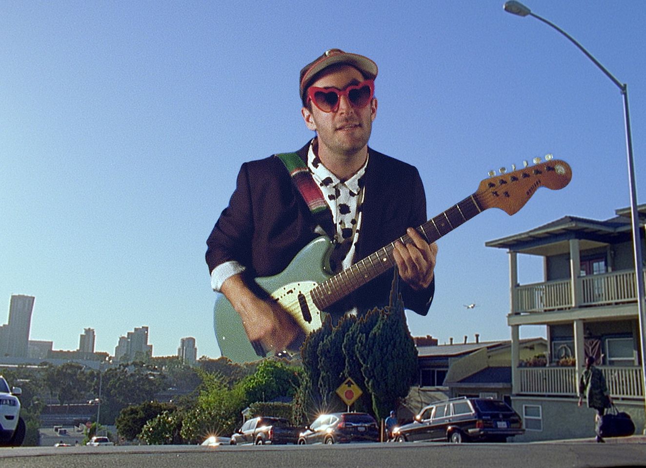Hether photo playing guitar superimposed over the San Diego skyline