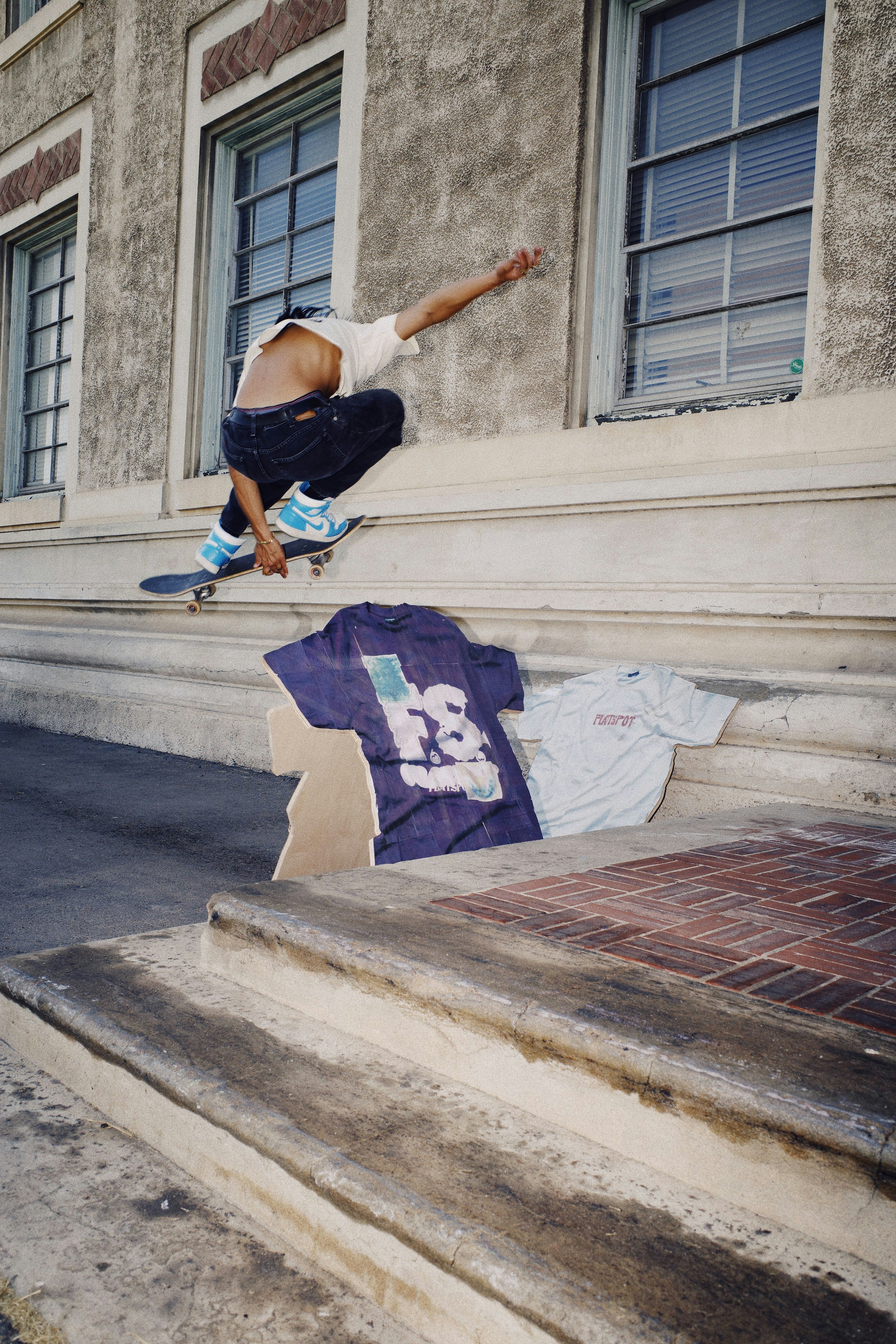 Flatspot AW21 Collection skateboarder ollie over printed wood cut-outs of the graphic tees